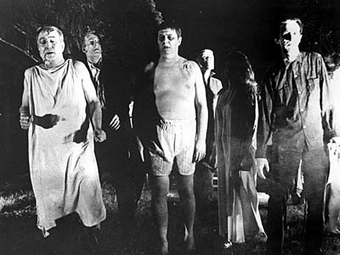  Zombies as portrayed in the movie "Night of the Living Dead". The zombies swarm around the house, searching for living human flesh.