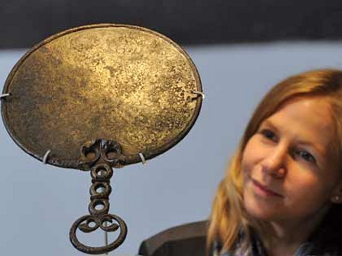 The mirror is made from bronze and is decorated with a symmetrical 'Celtic' or La Tene design. The decoration is on the back of the mirror, with the polished side where you saw your reflection on the other side.