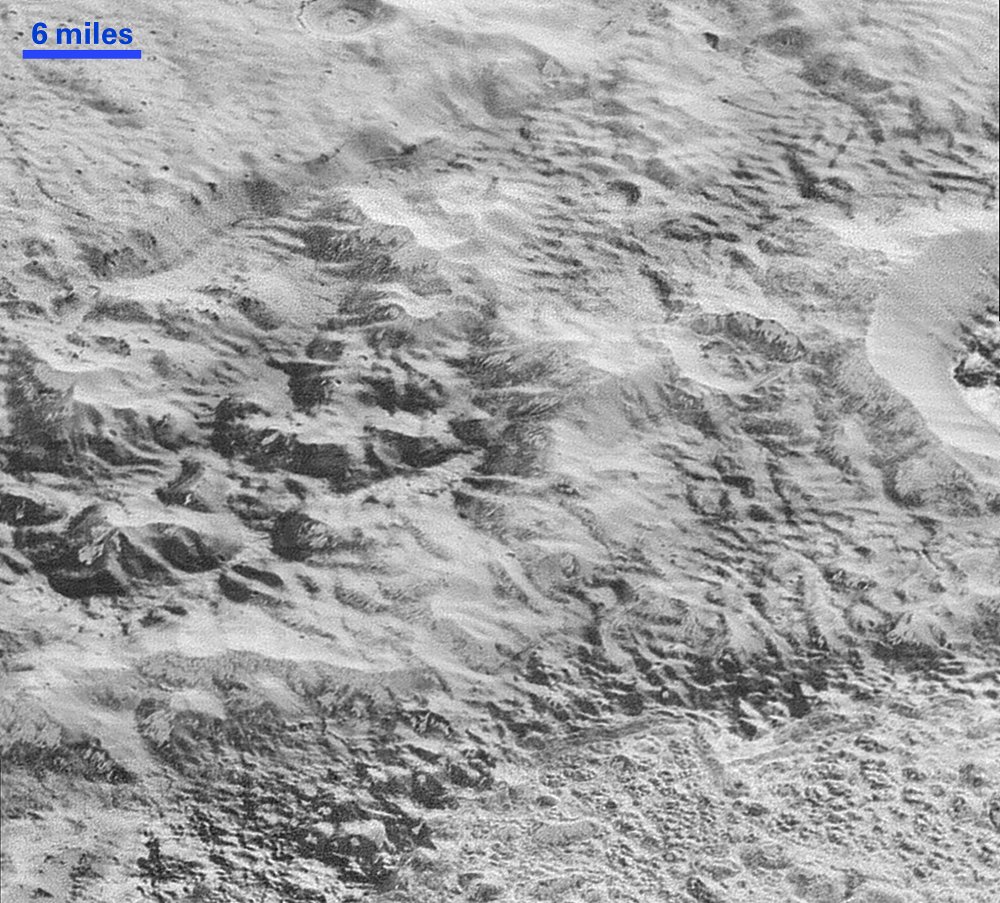 Erosion and faulting has sculpted portions of Pluto’s icy crust into rugged badlands. The prominent 1.2-mile-high cliff at the top, running from left to upper right, is part of a great canyon system that stretches for hundreds of miles across Pluto’s northern hemisphere. Credit: NASA/Johns Hopkins University Applied Physics Laboratory/Southwest Research Institute