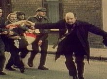 Father Edward Daly waving a blood-stained white handkerchief while trying to escort the mortally wounded Jackie Duddy to safety. Credits: Wikipedia