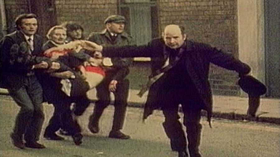 Father Edward Daly waving a blood-stained white handkerchief while trying to escort the mortally wounded Jackie Duddy to safety. Credits: Wikipedia