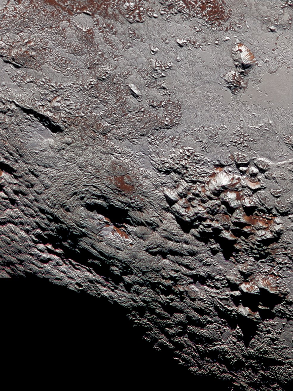 This composite image of a possible ice volcano on Pluto includes pictures taken by the New Horizons spacecraft’s Long Range Reconnaissance Imager (LORRI) on July 14, 2015, from a range of about 30,000 miles (48,000 kilometers), showing features as small as 1,500 feet (450 meters) across. Sprinkled across the LORRI mosaic is enhanced color data from the Ralph/Multispectral Visible Imaging Camera (MVIC), from a range of 21,000 miles (34,000 kilometers) and at a resolution of about 2,100 feet (650 meters) per pixel. The entire scene is 140 miles (230 kilometers) across. Image credit: NASA/JHUAPL/SwRI