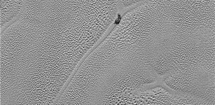 Transmitted to Earth on Dec. 24, 2015, this image from the Long Range Reconnaissance Imager (LORRI) extends New Horizons’ highest-resolution swath of Pluto to the center of Sputnik Planum, the informally named plain that forms the left side of Pluto’s “heart.” Mission scientists believe the pattern of the cells stems from the slow thermal convection of the nitrogen-dominated ices. The darker patch at the center of the image is likely a dirty block of water ice “floating” in denser solid nitrogen, and which has been dragged to the edge of a convection cell. Also visible are thousands of pits in the surface, which scientists believe may form by sublimation. Credits: NASA/JHUAPL/SwRI