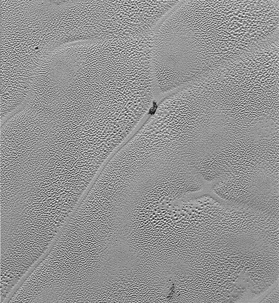 Transmitted to Earth on Dec. 24, 2015, this image from the Long Range Reconnaissance Imager (LORRI) extends New Horizons’ highest-resolution swath of Pluto to the center of Sputnik Planum, the informally named plain that forms the left side of Pluto’s “heart.” Mission scientists believe the pattern of the cells stems from the slow thermal convection of the nitrogen-dominated ices. The darker patch at the center of the image is likely a dirty block of water ice “floating” in denser solid nitrogen, and which has been dragged to the edge of a convection cell. Also visible are thousands of pits in the surface, which scientists believe may form by sublimation. Credits: NASA/JHUAPL/SwRI