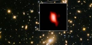 This image shows the galaxy cluster MACS J1149.5+2223 taken with the NASA/ESA Hubble Space Telescope; the inset image is the very distant galaxy MACS1149-JD1, seen as it was 13.3 billion years ago and observed with ALMA. Here, the oxygen distribution detected with ALMA is depicted in red. Credit: ALMA (ESO/NAOJ/NRAO), NASA/ESA Hubble Space Telescope, W. Zheng (JHU), M. Postman (STScI), the CLASH Team, Hashimoto et al.