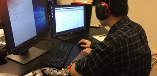 Kevin Tan, a participant in the study, learns English sounds through haptic communication technology developed by Purdue researchers. The device plays specific sensations on the user’s forearm, as he notes the corresponding English phoneme, or the smallest unit of sound. (Image provided)