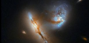 The pair of strange, luminescent creatures at play in this image are actually galaxies — realms of millions upon millions of stars.