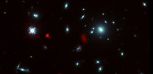 The galaxy cluster RXCJ0600-2007 taken by the NASA/ESA Hubble Space Telescope, combined with gravitational lensing images of the distant galaxy RXCJ0600-z6, 12.4 billion light-years away, observed by ALMA (shown in red). Due to the gravitational lensing effect by the galaxy cluster, the image of RXCJ0600-z6 was intensified and magnified, and appeared to be divided into three or more parts. Credit: ALMA (ESO/NAOJ/NRAO), Fujimoto et al., NASA/ESA Hubble Space Telescope