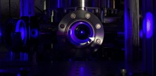 One of the first steps in creating the optical atomic clocks used in this study is to cool strontium atoms to near absolute zero in a vacuum chamber, which makes them appear as a glowing blue ball floating in the chamber. Credit: Shimon Kolkowitz